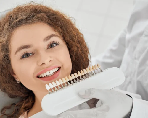 woman-smiling-while-male-dentist-keeping-teeth-color-range (1)